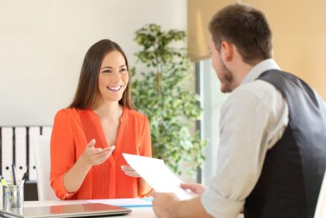 female applicant in orange top talking to male interviewer