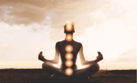 man with aligned chakras sitting and meditating