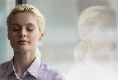 blonde woman closing eyes and meditating