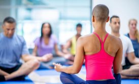 female instructor leading a group of people in a seated meditation