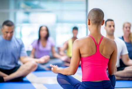 female instructor leading a group of people in a seated meditation