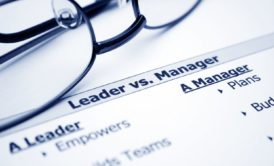 a piece of paper with the label leader versus manager in the background and a pair of glasses with black frame