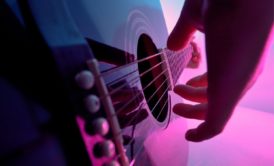 close up of hand plucking guitar strings