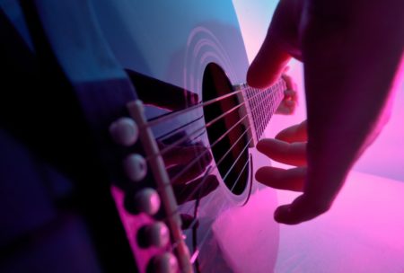 close up of hand plucking guitar strings