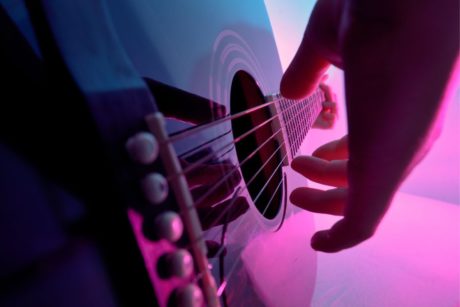 close up of hand plucking guitar strings