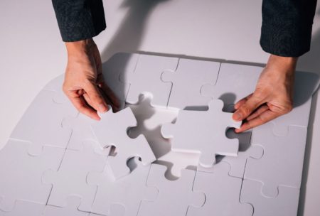 man putting two pieces of white giant jigsaw puzzle together