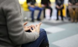 woman in brown sweater talking in group therapy