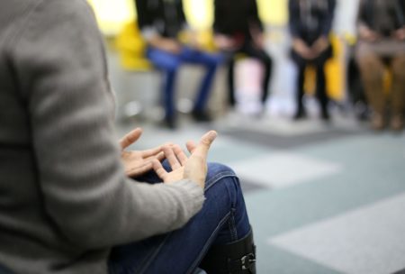 woman in brown sweater talking in group therapy