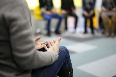 woman in brown sweater talking in group therapy