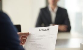 female interviewer in blue suit looking at chinese applicant's resume