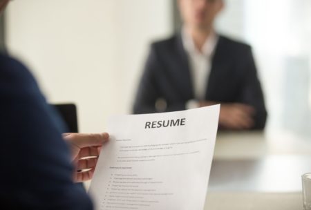 female interviewer in blue suit looking at chinese applicant's resume