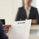 female interviewer in blue suit looking at chinese applicant's resume