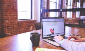 man in light brown suit typing on laptop