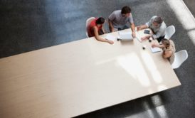 team meeting with four members at edge of large table