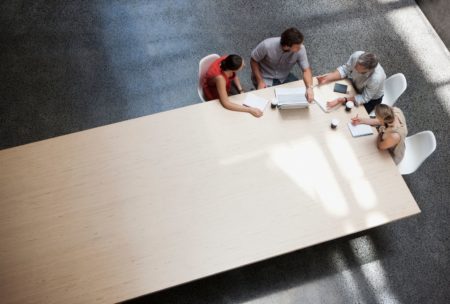 team meeting with four members at edge of large table