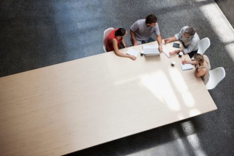 team meeting with four members at edge of large table