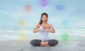 woman in white top and black yoga pants sitting down and meditating on the floor