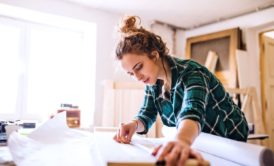 female entrepreneur wearing green plaid top in wood workshop