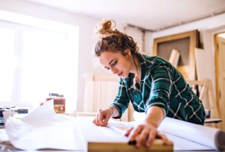 female entrepreneur wearing green plaid top in wood workshop