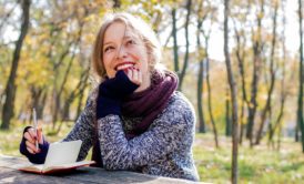 smiling woman wearing purple sweater and scarf outdoors