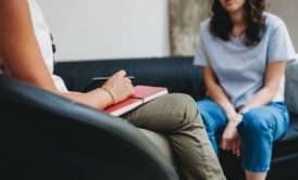 woman in light blue top talking to a female therapist in white
