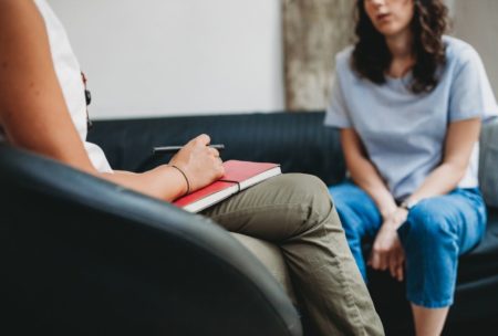 woman in light blue top talking to a female therapist in white