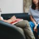 woman in light blue top talking to a female therapist in white