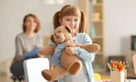 girl smiling and hugging a teddy bear