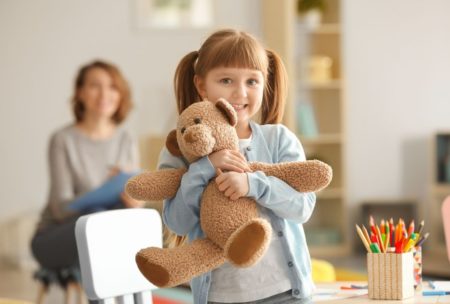 girl smiling and hugging a teddy bear