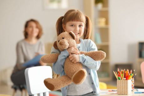 girl smiling and hugging a teddy bear