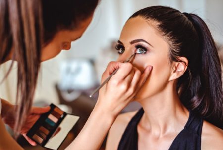 makeup artist applying makeup on woman wearing black top