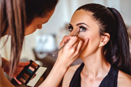 makeup artist applying makeup on woman wearing black top