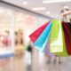 womans hand carrying multi colored shopping bags