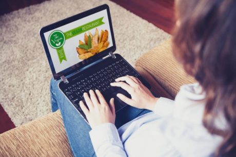 woman in white top creating restaurant website on black laptop