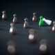 green chess pawn amidst black pawns