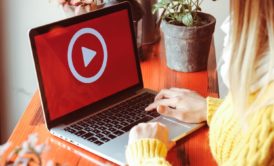 video marketer wearing yellow sweater typing on laptop