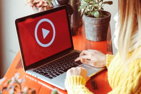 video marketer wearing yellow sweater typing on laptop