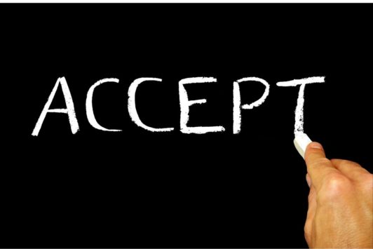 hand writing the word accept on blackboard