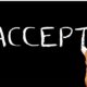 hand writing the word accept on blackboard