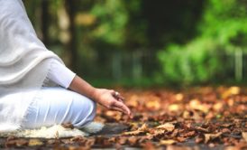 mindfulness practitioner wearing white and meditating in the woods