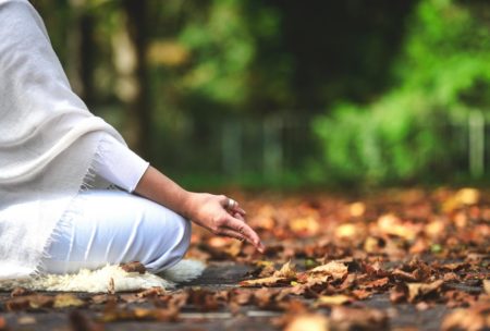 mindfulness practitioner wearing white and meditating in the woods