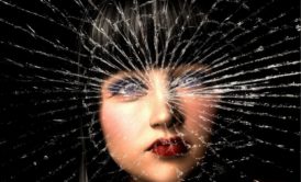 woman's face behind broken glass