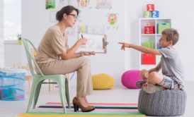 female child counselor showing an illustration to a sitting boy