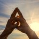 Hands of a hand mudra yoga practitioner with a sunset in the background