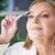 mature woman in white bathrobe putting on makeup