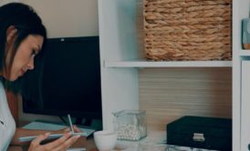 woman wearing white top writing on desk