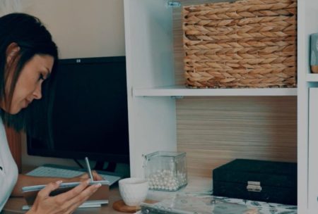 woman wearing white top writing on desk