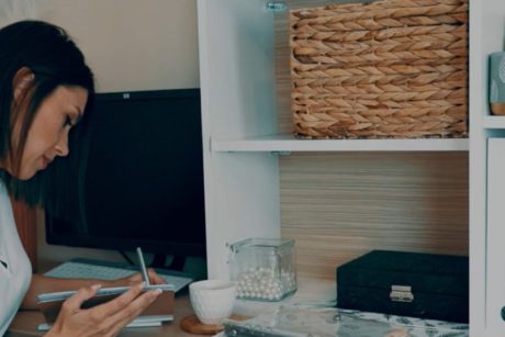 woman wearing white top writing on desk