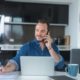 man in blue top talking on phone and writing on paper