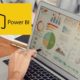 power bi logo and person creating chart on laptop